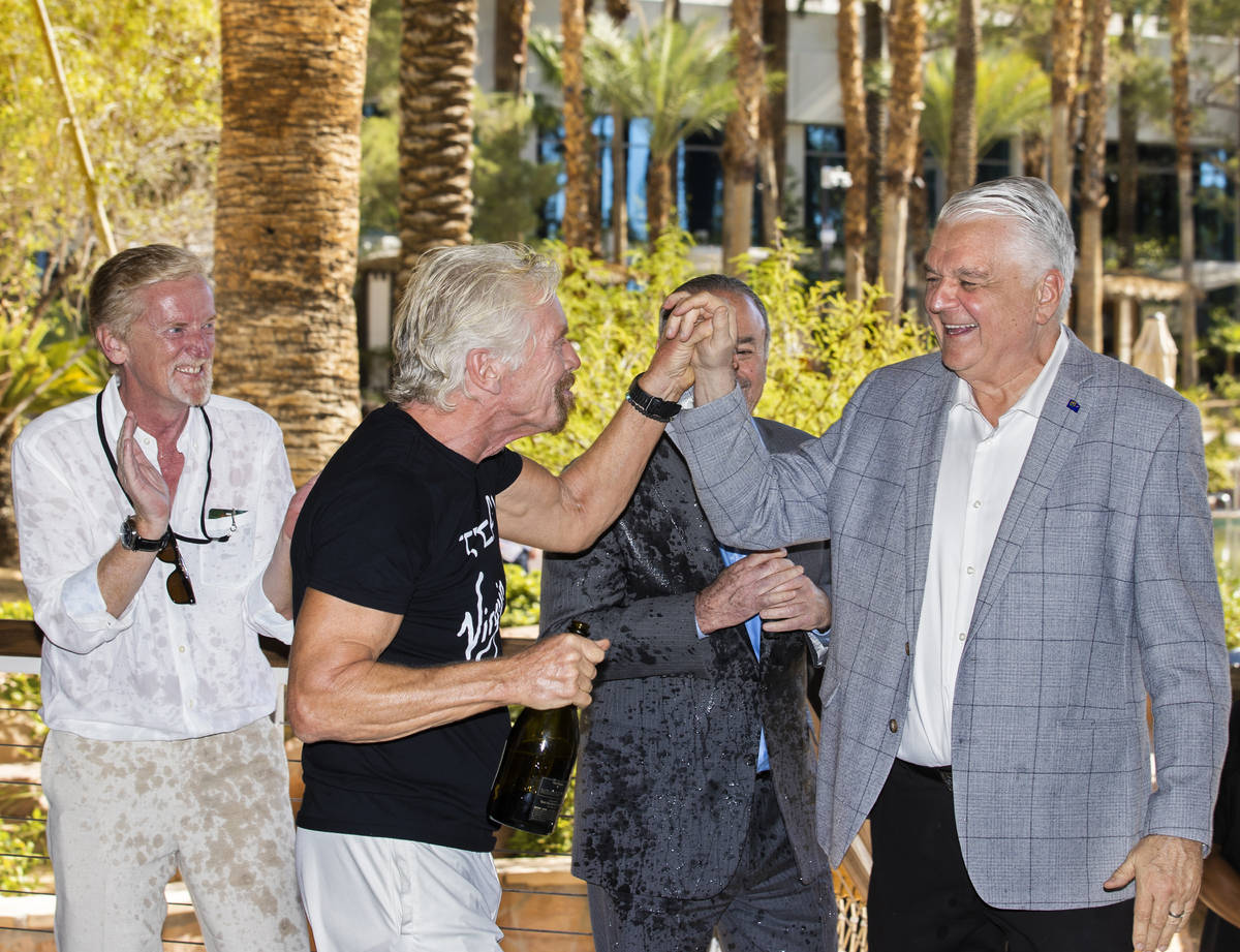 Sir Richard Branson, second from left, founder of Virgin Group, high fives Gov. Steve Sisolak a ...