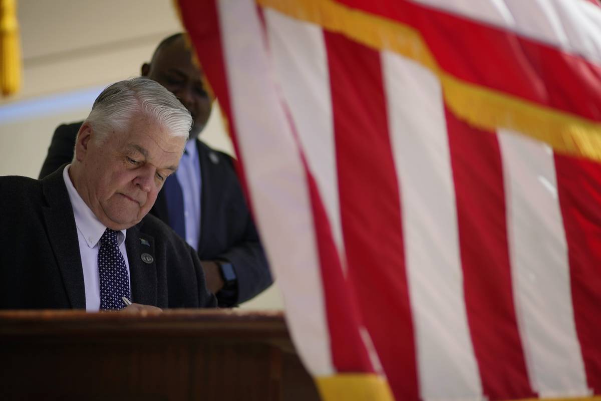 Nevada Democratic Gov. Steve Sisolak signs one of several bills into law at a signing ceremony ...