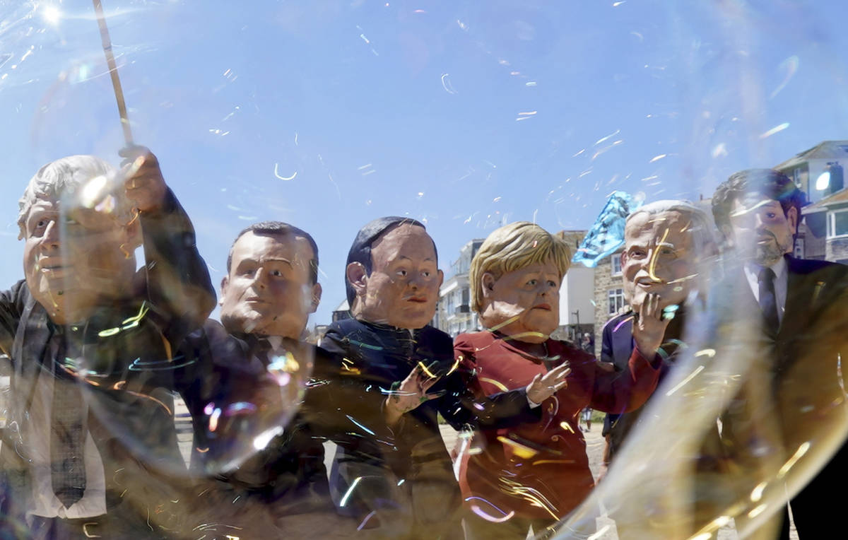 Protestors wear giant heads portraying the leaders of the G7 as they play with bubbles during a ...