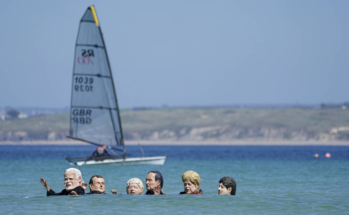 Protestors wearing giant heads portraying G7 leaders swim in the water during a demonstration o ...