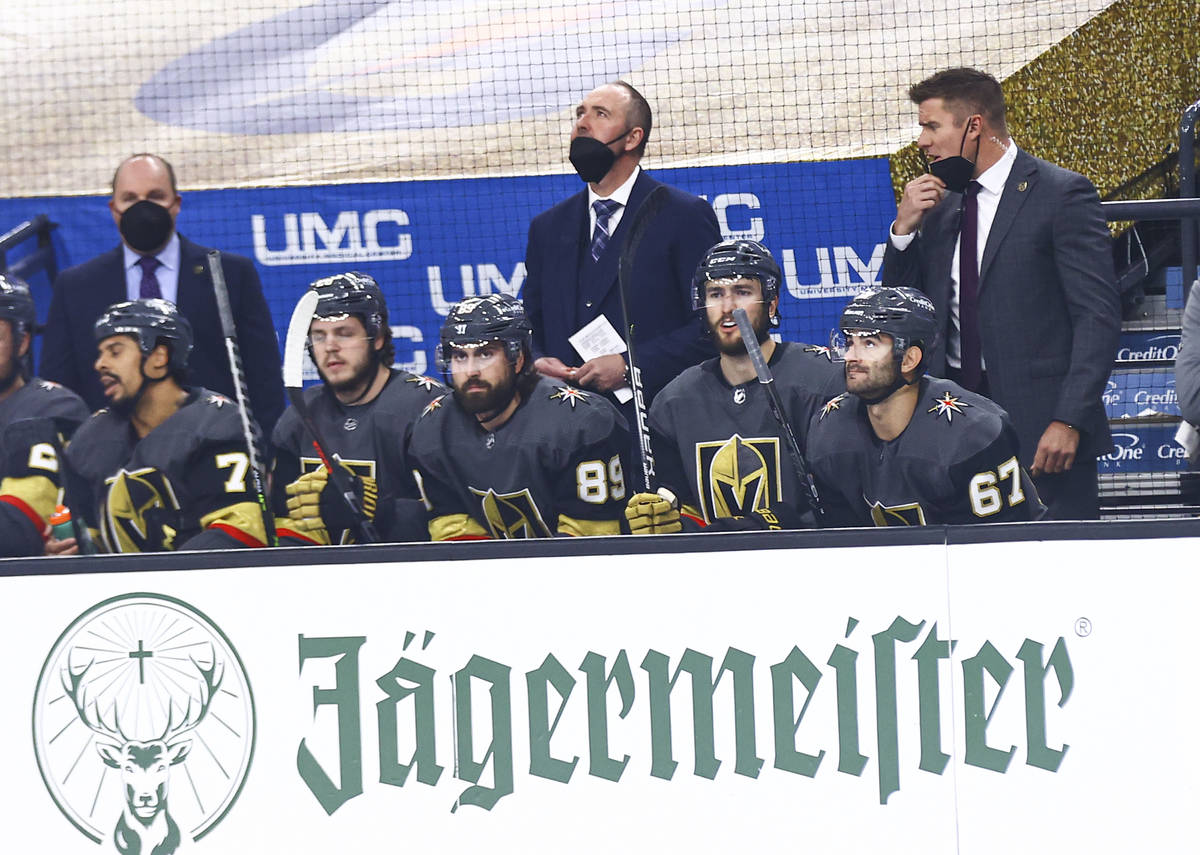 Golden Knights head coach Pete DeBoer, center, looks on from the bench during the first period ...