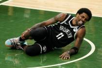 Brooklyn Nets' Kyrie Irving holds his leg after being injured during the first half of Game 4 o ...