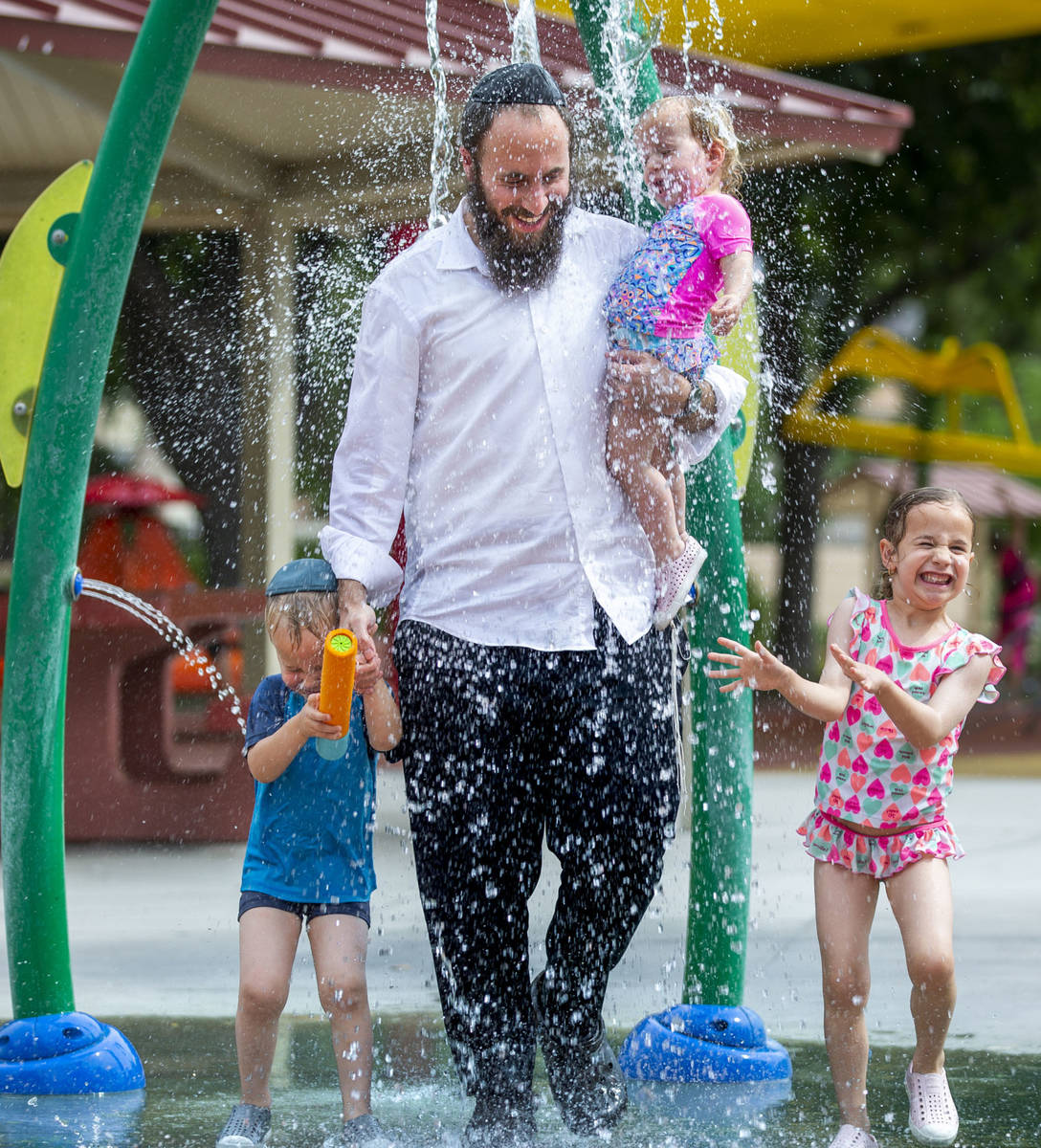 Rabbi Motti Harlig holds his daughter Shula, 1, with other children Rivka, 5 (right), and Mende ...