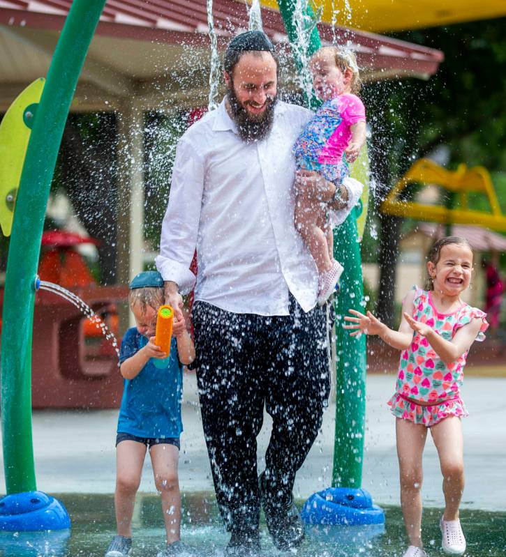 Rabbi Motti Harlig holds his daughter Shula, 1, with other children Rivka, 5 (right), and Mende ...