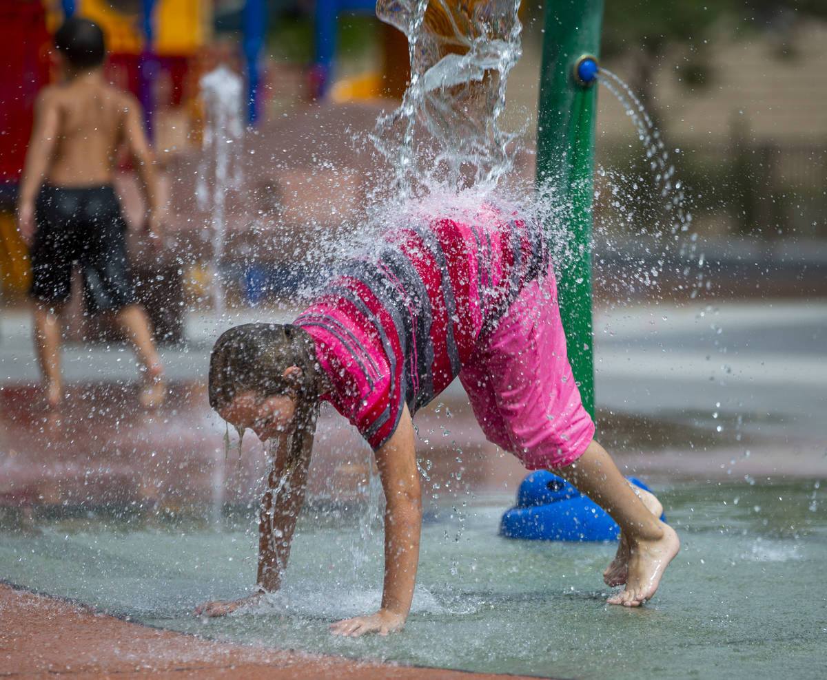 Ellie Bagenski, 7, of Baker City, Oregon, is pounded with water on the splash pad at Bob Baskin ...