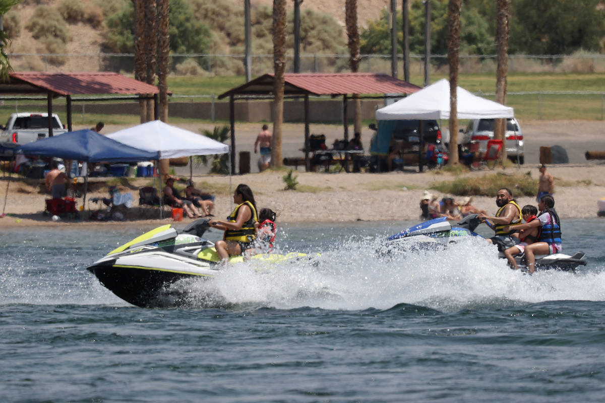 People ride jet skis on the Colorado River and across from the Colorado River Heritage Greenway ...