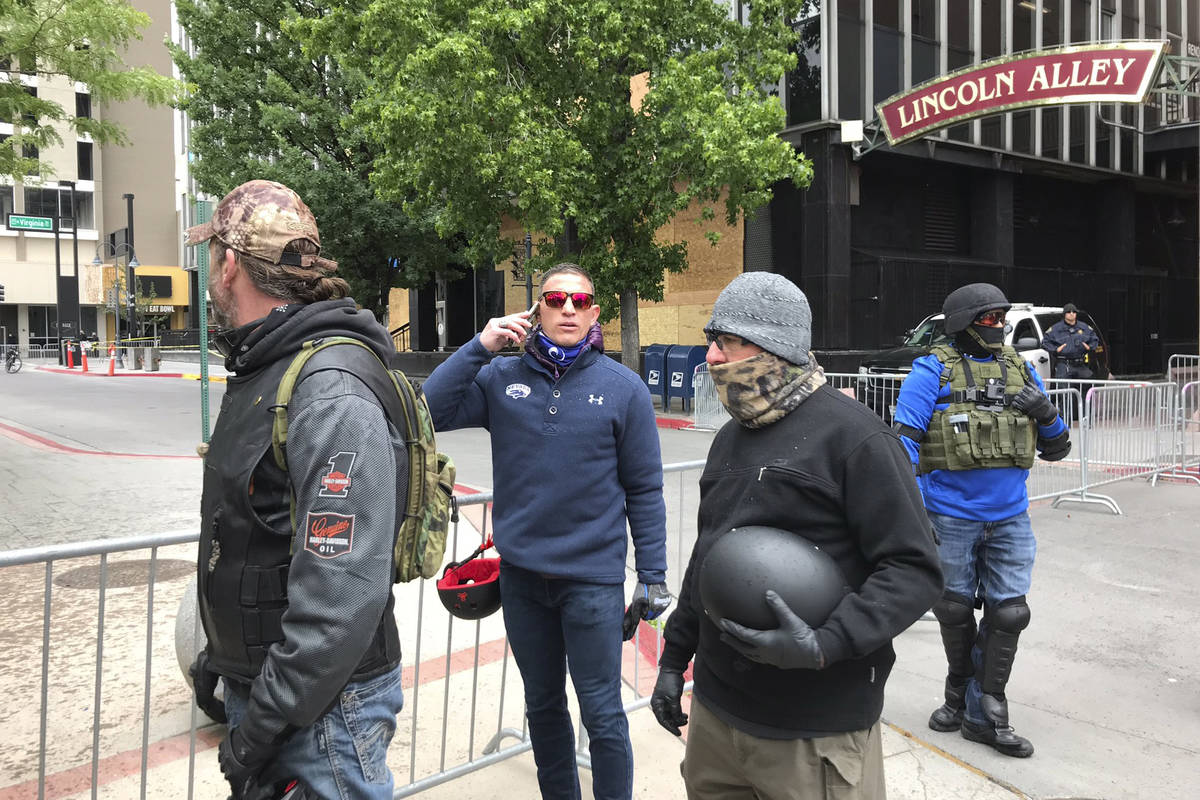 Joey Gilbert holds his phone while standing with others near a Black Lives Matter Peace Vigil i ...