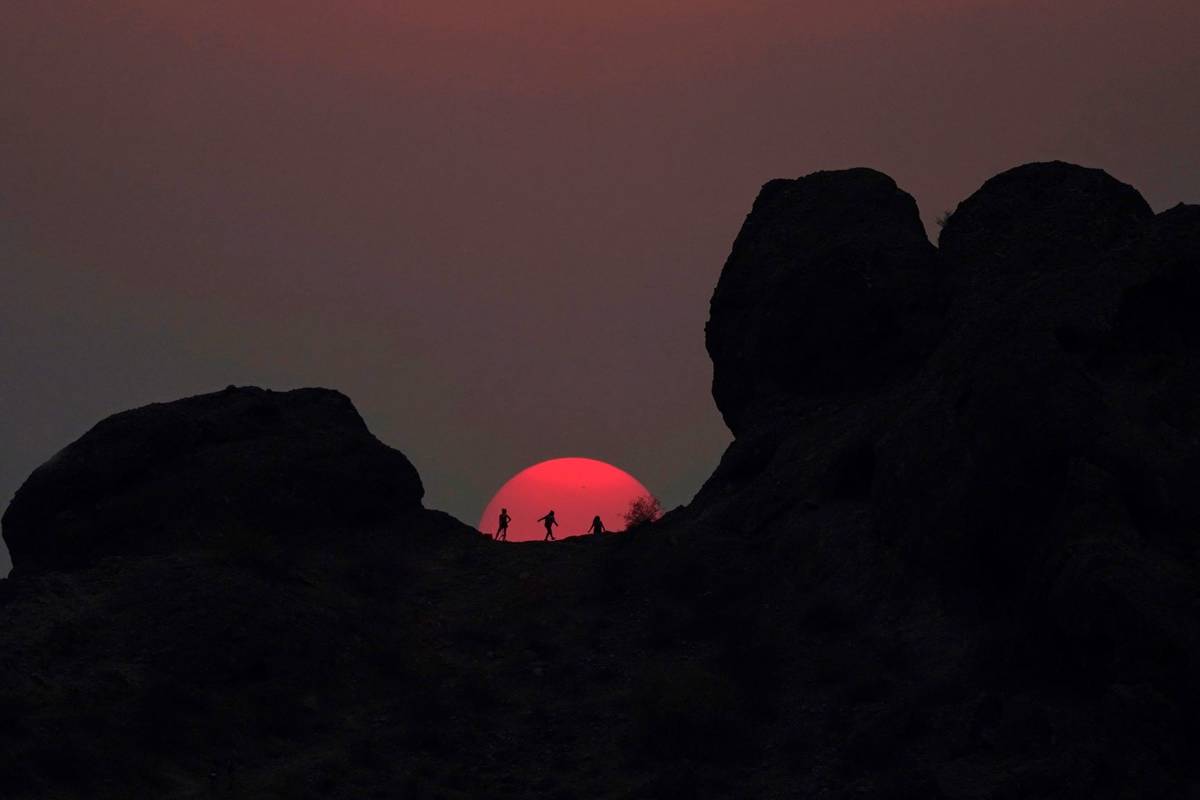 Hikers pause to watch the sunset at Papago Park during a heatwave where temperatures reached 11 ...