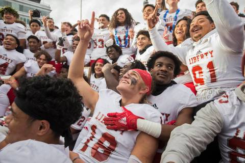 Liberty junior quarterback Daniel Britt (18) points to the sky as he celebrates with teammates ...