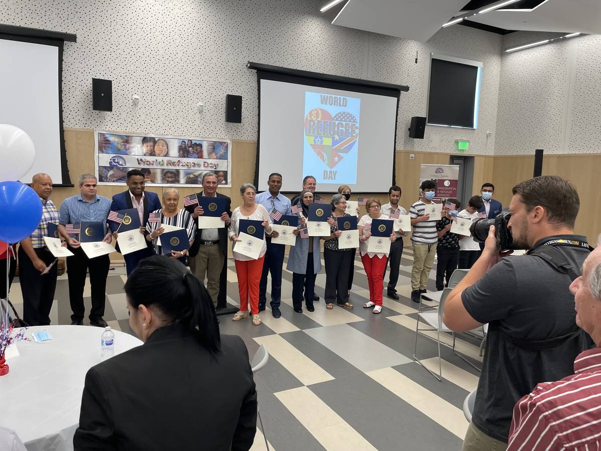 Newly naturalized U.S. citizens pose with American flags and congratulatory certificates from e ...