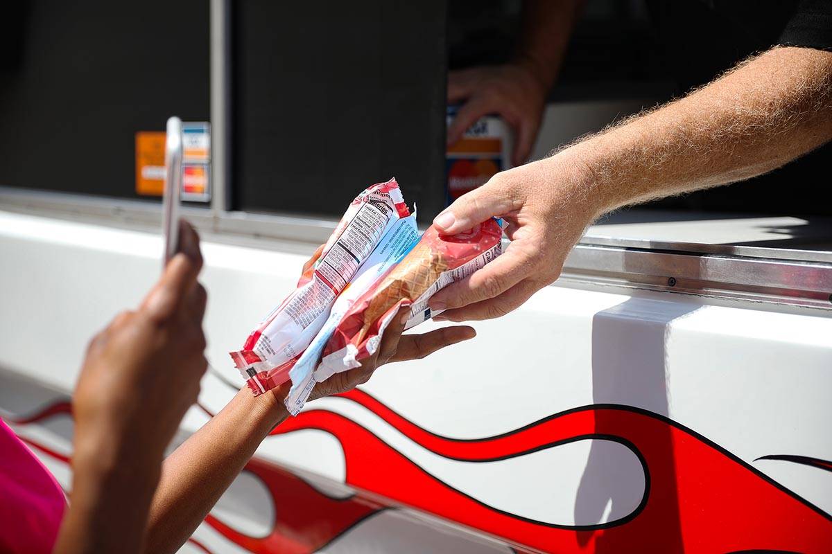 Al Davis, owner of Fat Daddys Ice Cream truck, hands ice cream to Jazmine Eady outside Caliber ...