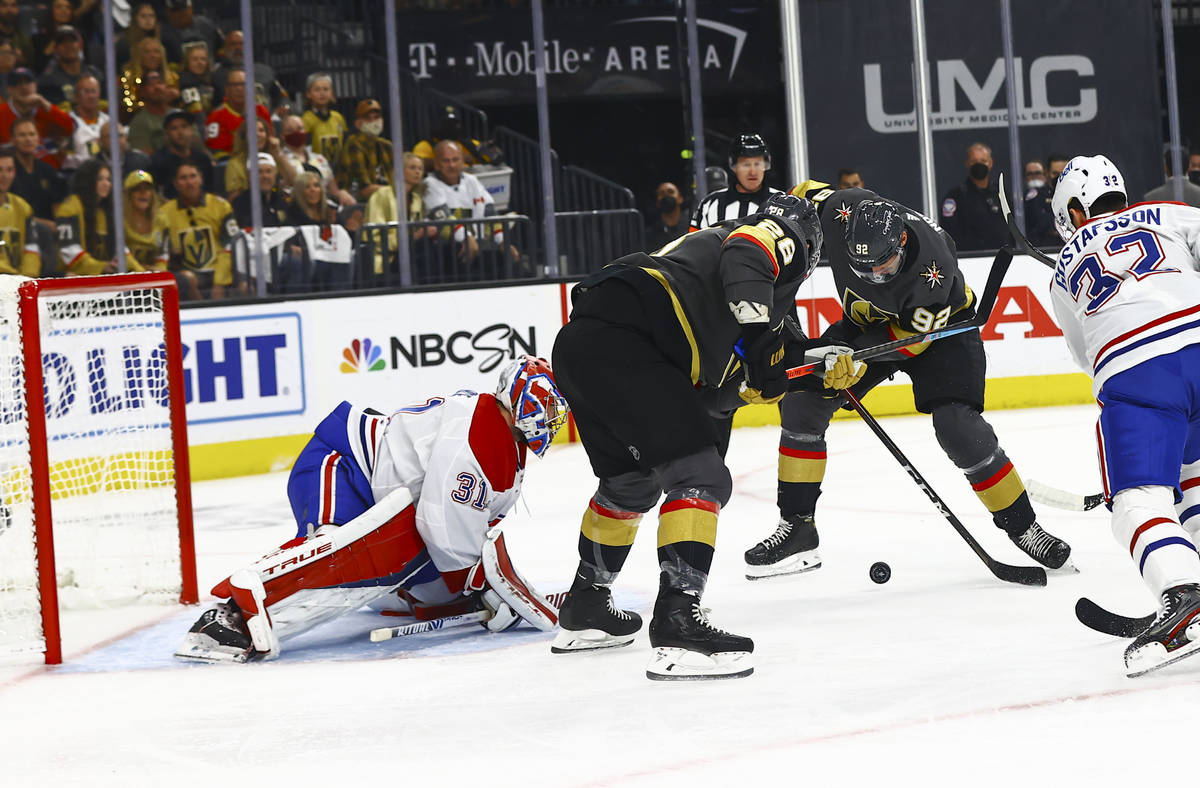 Golden Knights' William Carrier, second from left, and Tomas Nosek (92), try to get the puck i ...