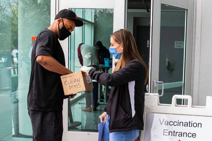 Ann Beck, right, a volunteer, hands out clean pens to a man who came to receive a COVID-19 vacc ...