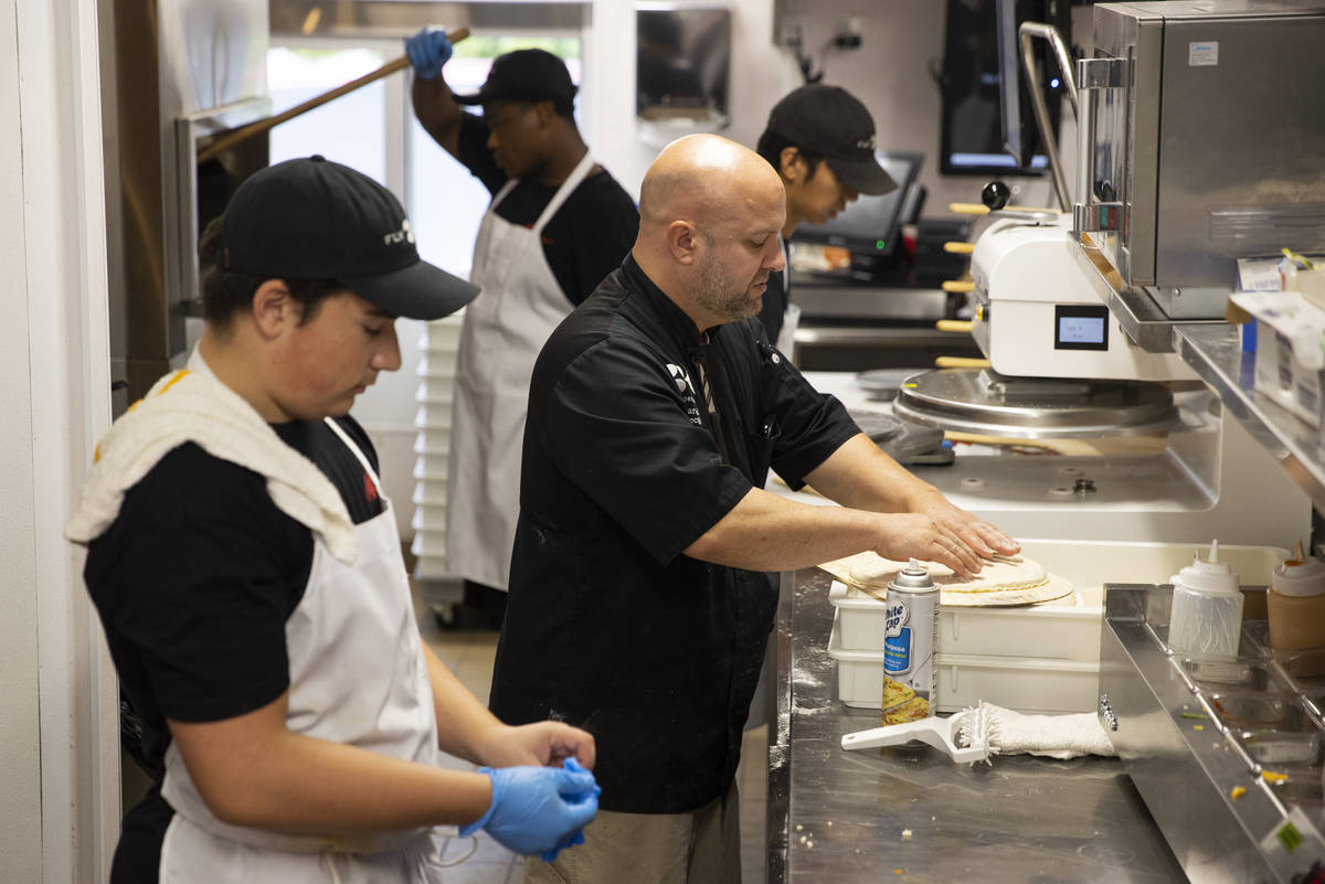 Executive chef Aaron Raeder, center, trains crew members in the kitchen of the the Fly Pie pizz ...