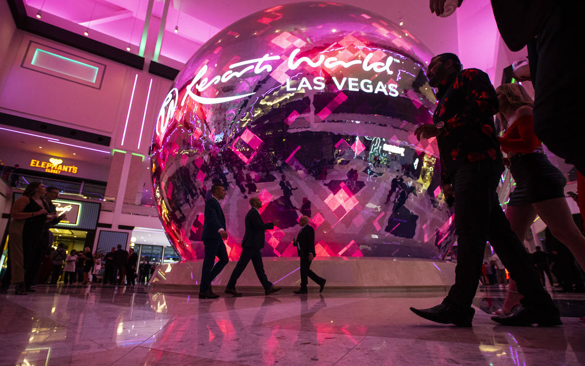 People walk by the illuminated sphere in The District during the opening night of Resorts World ...