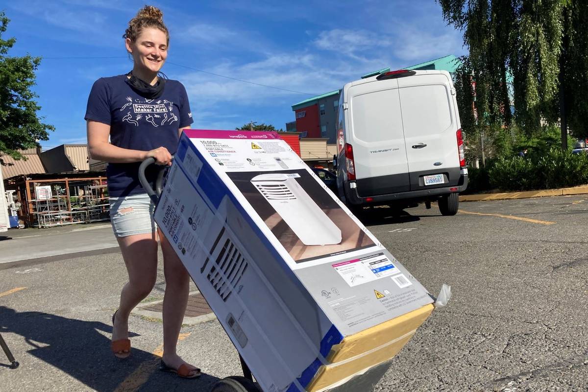 Sarah O'Sell transports her new air conditioning unit to her nearby apartment on a dolly in Sea ...