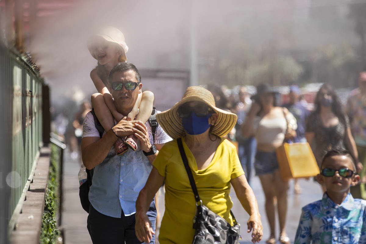 Visitors cool off in the misters outside the Paris Las Vegas as the temperature rises on Saturd ...