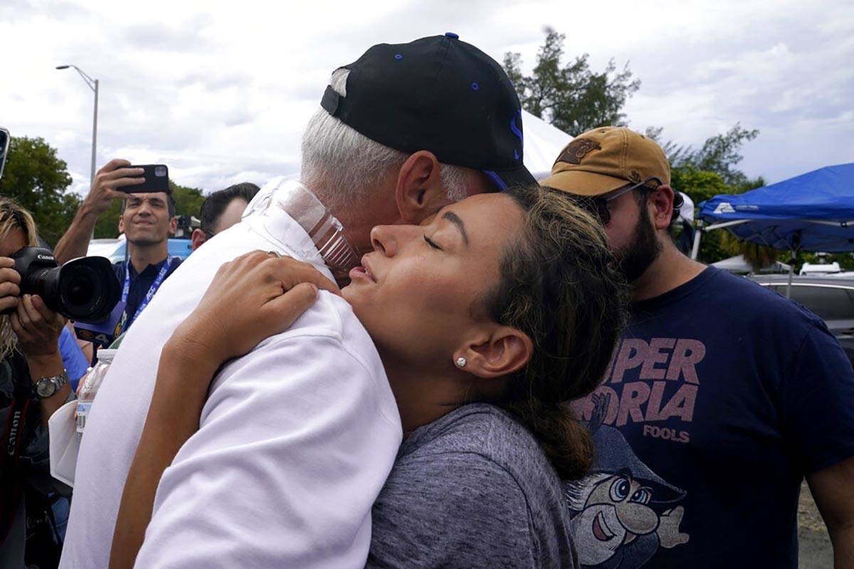 Rachel Spiegel, right, is hugged by the Mayor of Surfside Charles Burkett, left, as she asks fo ...