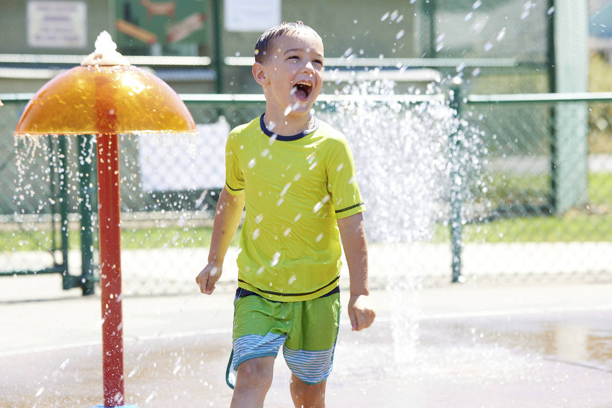 Hunter Sack, 7, runs through the water at Max Patterson park to escape from the heat during a r ...