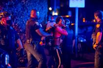 A man is arrested while out a few hours past curfew in Miami Beach, Fla., on Sunday, March 21, ...