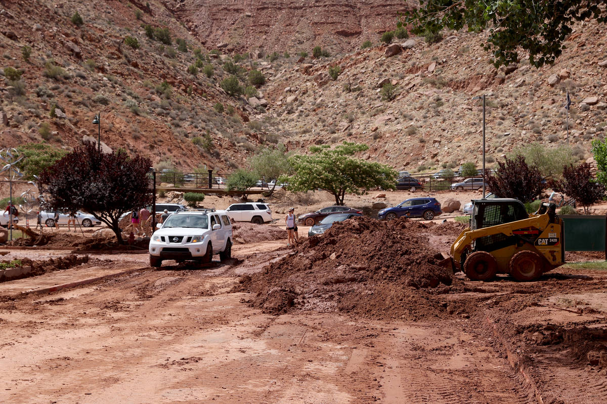Workers clear mud and debris in Zion Canyon Village in Zion National Park near Springdale, Utah ...