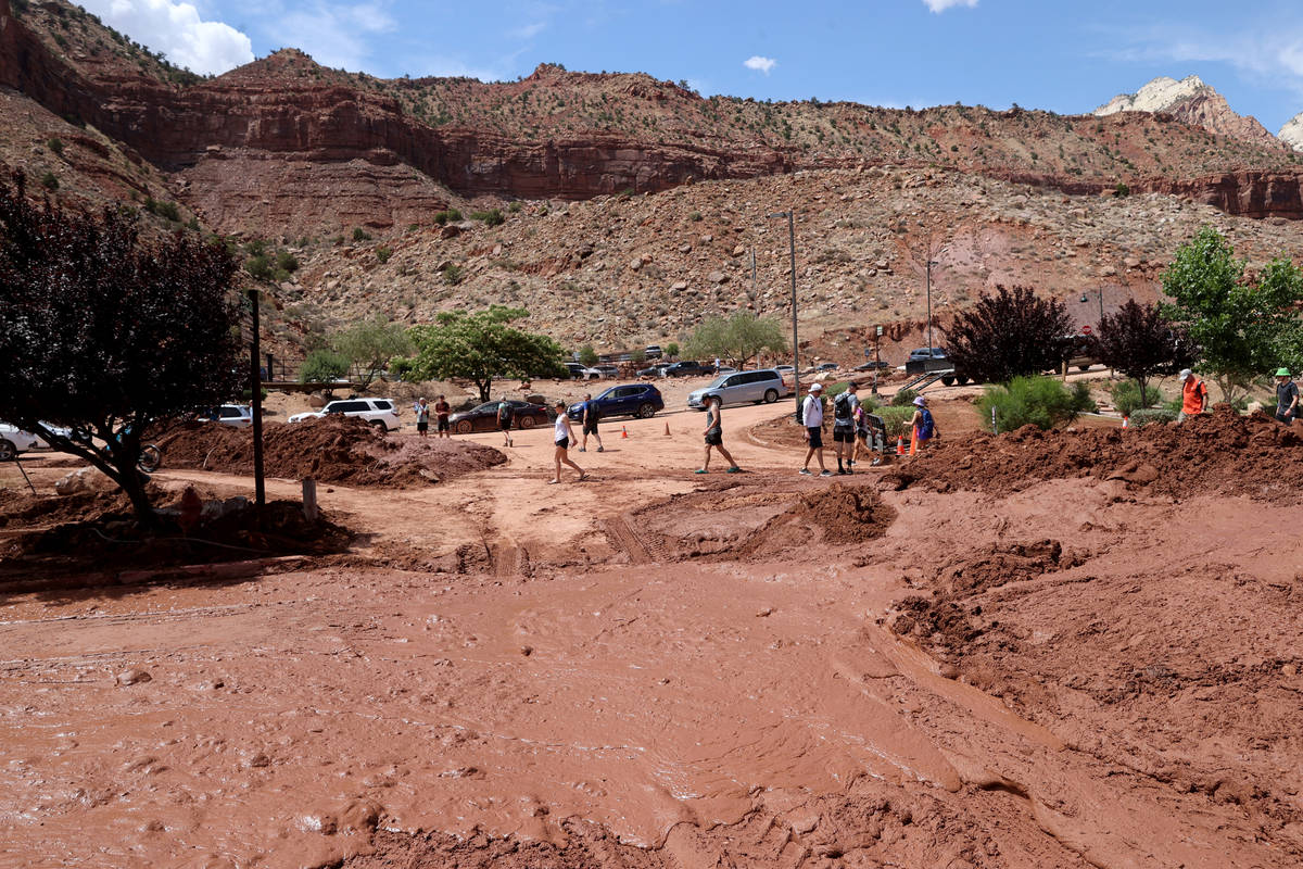 Workers clear mud and debris in Zion Canyon Village in Zion National Park near Springdale, Utah ...