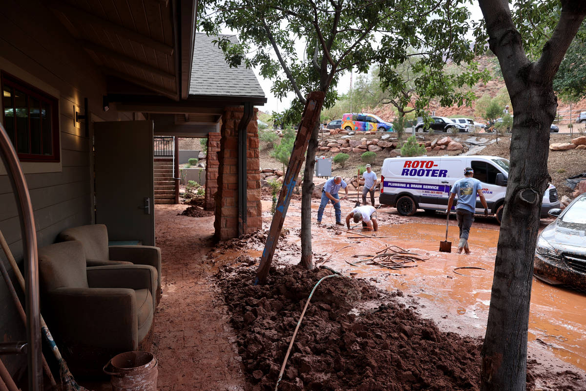 Workers clear a drain and work to free stuck cars in Zion Canyon Village in Zion National Park ...