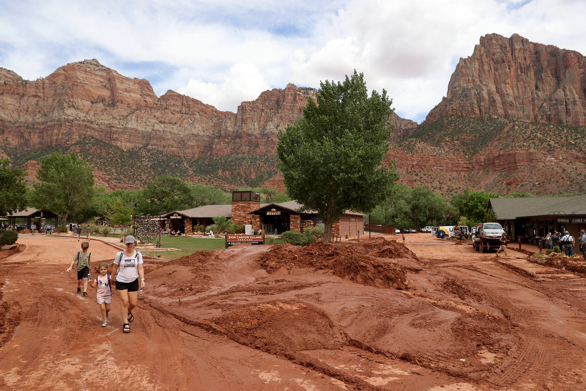 People walk past mud and debris in Zion Canyon Village in Zion National Park near Springdale, U ...