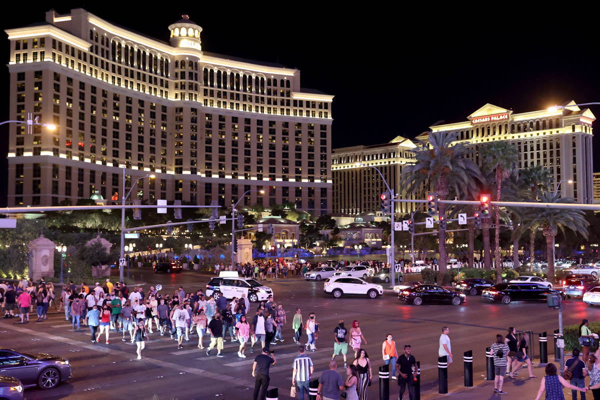 People walk between the Bellagio and Planet Hollywood Resort on the Strip in Las Vegas Friday, ...