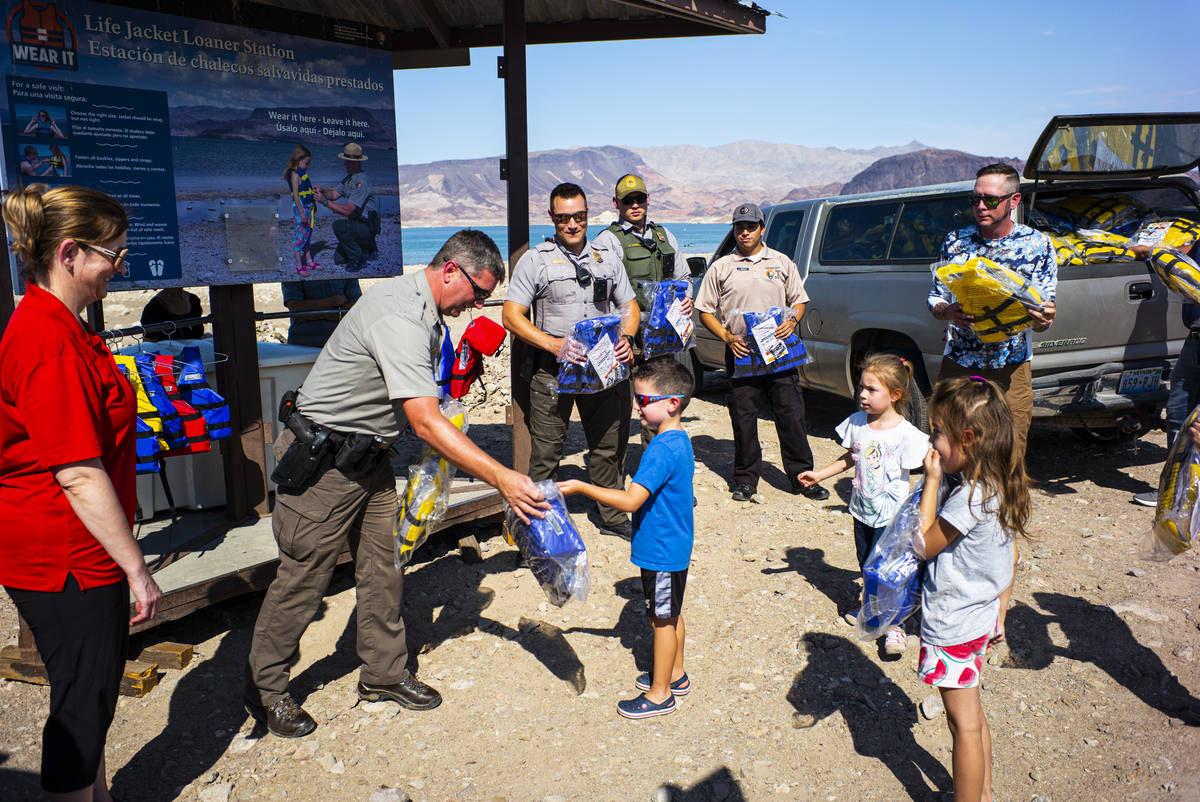 Liam Cohen, 4, in blue, helps deliver lifejackets to park rangers, including Matt Stark, deputy ...