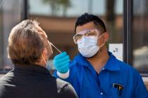 Practice Manager Jose Tirana conducts a COVID-19 test on a patient at Sahara West Urgent Care & ...