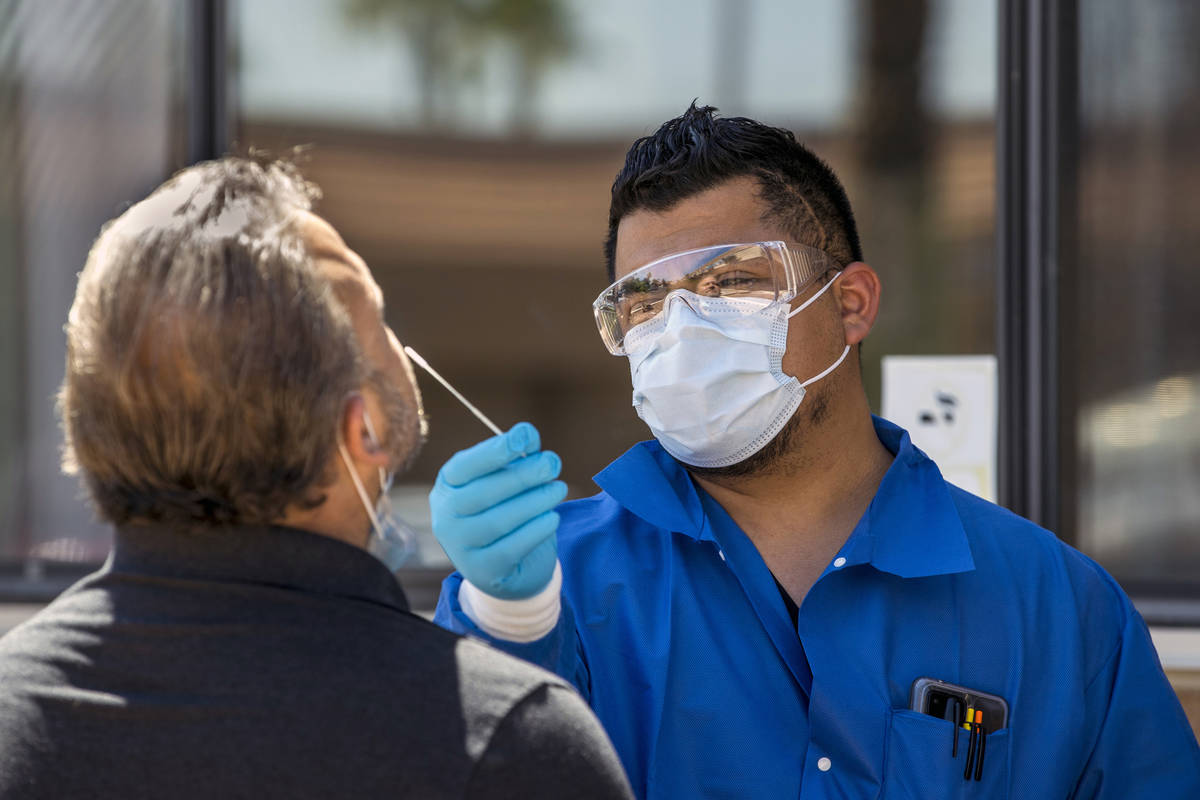 Practice Manager Jose Tirana conducts a COVID-19 test on a patient at Sahara West Urgent Care & ...
