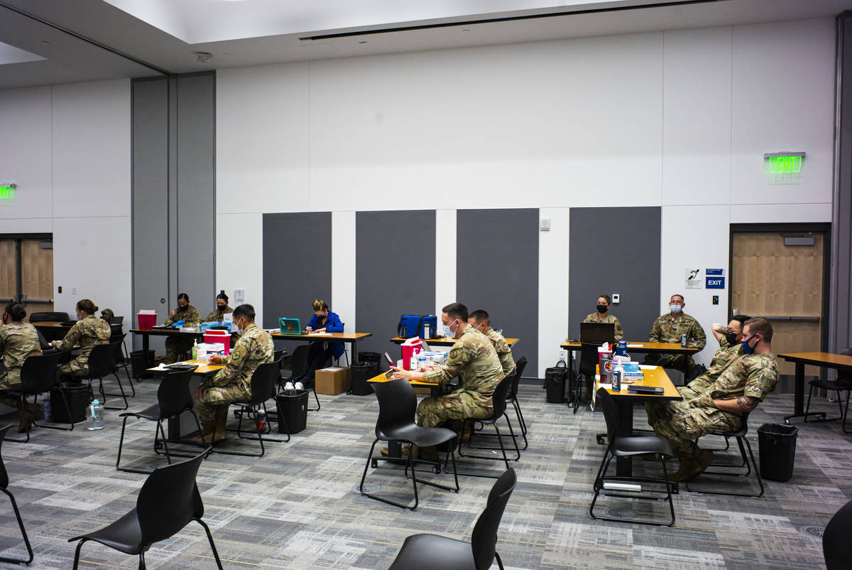 Members of the National Guard wait to distribute vaccines at a vaccination clinic at the Colleg ...