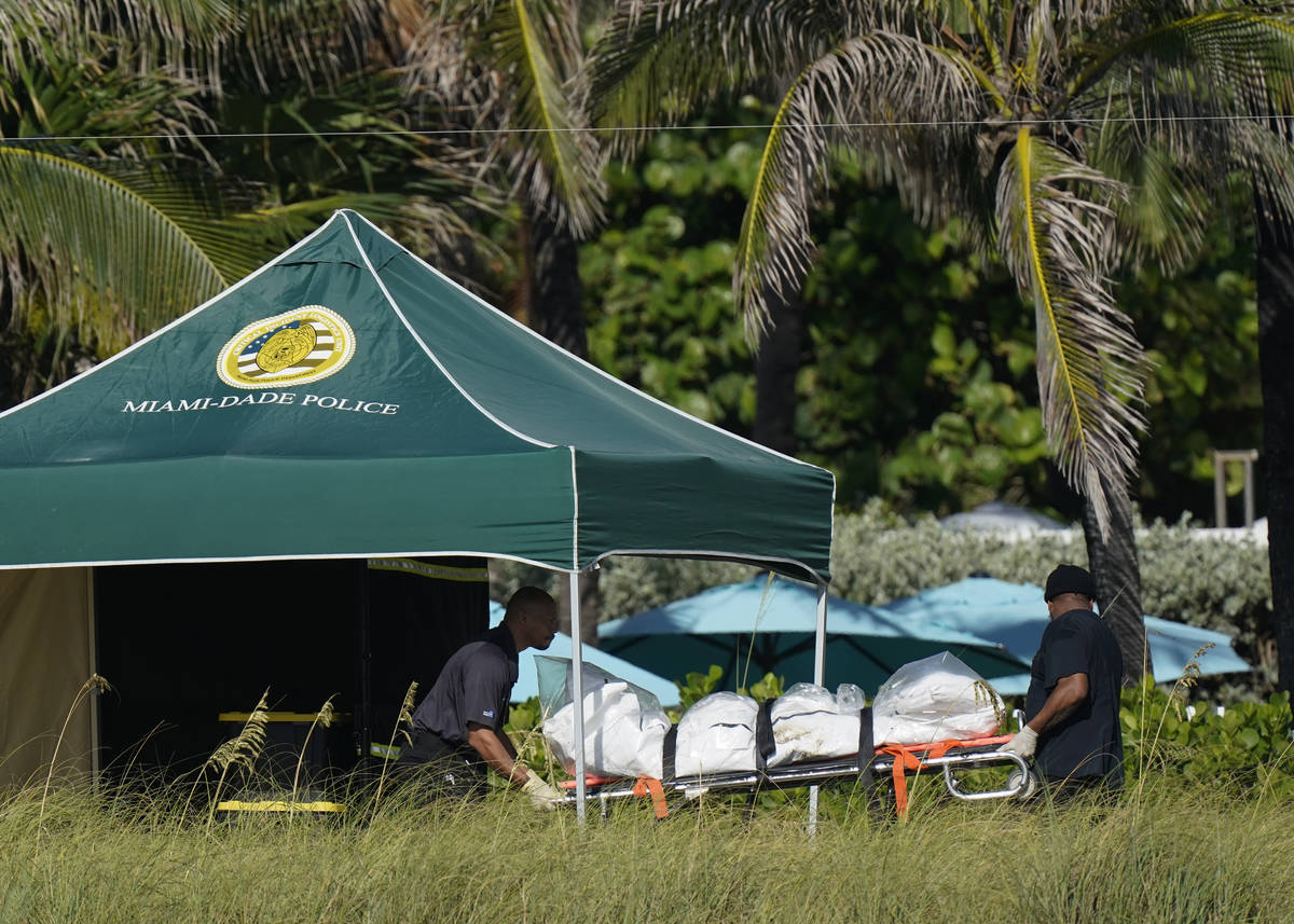 Workers transport a stretcher with remains extricated from the rubble, near the Champlain Tower ...