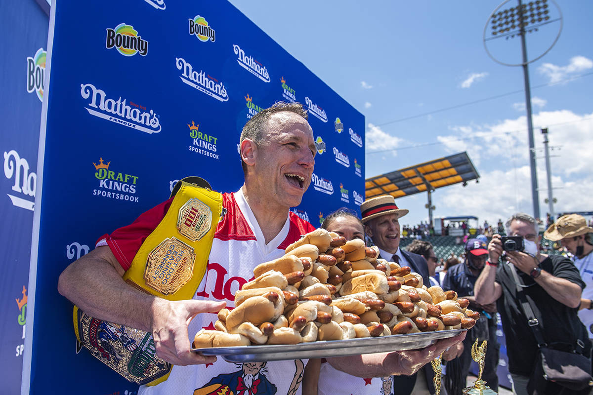 Winners Joey Chestnut and Michelle Lesco, obscured behind hot dogs, pose at the Nathan's Famous ...