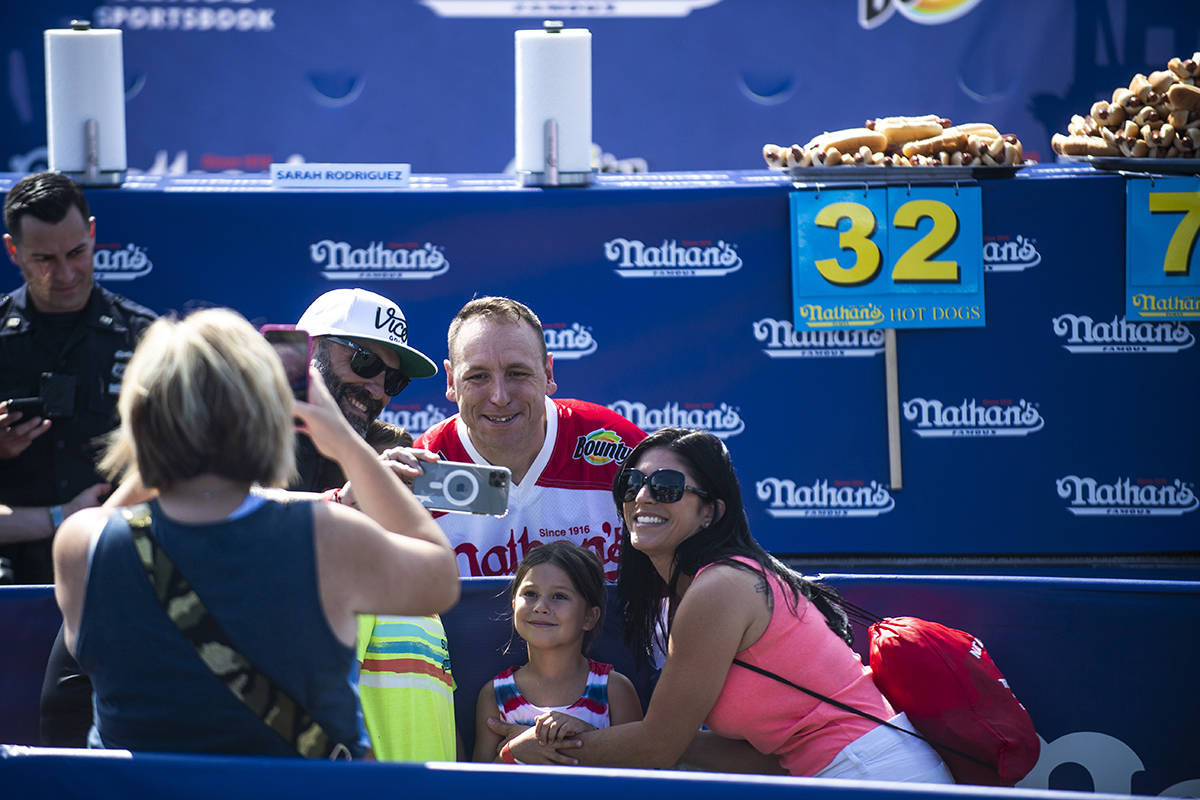 Joey Chestnut takes a photo with a family at the Nathan's Famous Fourth of July International H ...