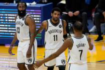 Brooklyn Nets guard Kyrie Irving, middle, gathers with guard James Harden (13) and forward Kevi ...