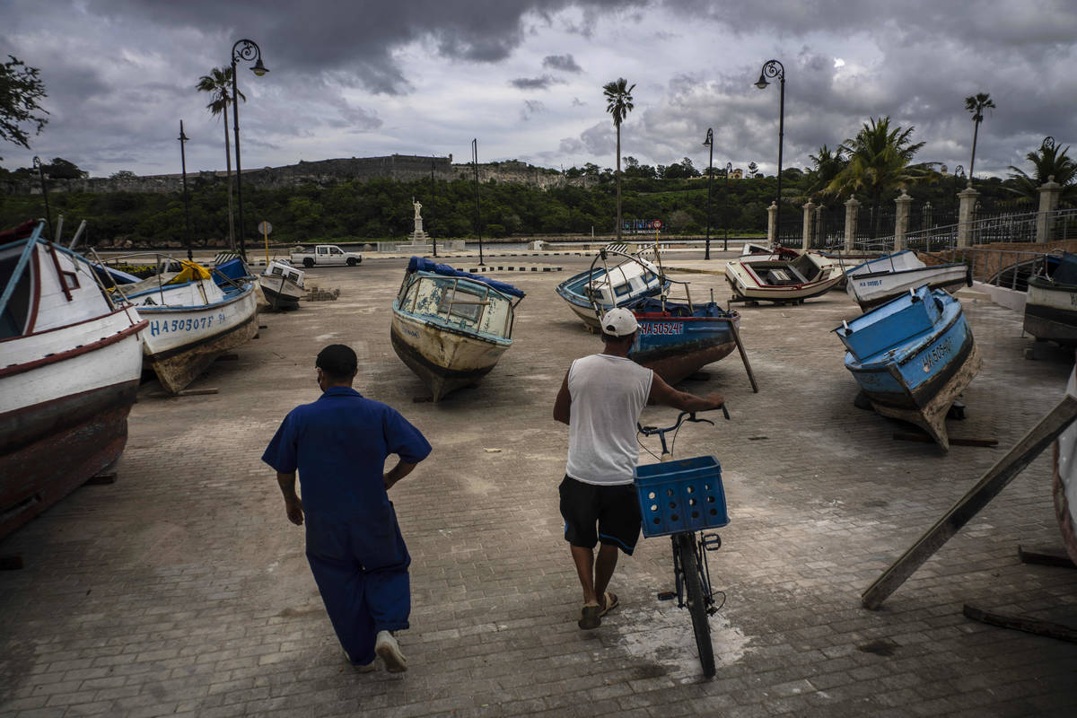 Fishermen inspect their boats after they have been taken out of the bay to avoid damage from th ...