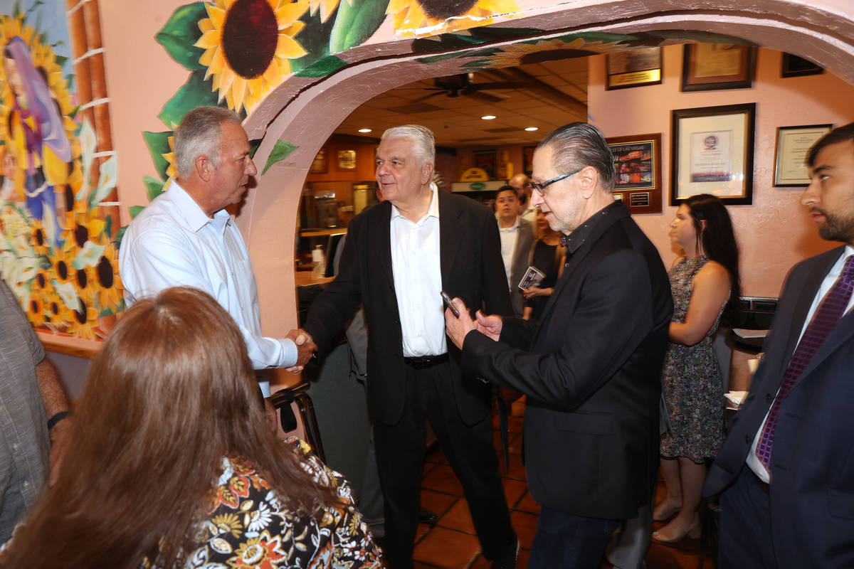 Gov. Steve Sisolak, center, greets Clark County District Attorney Steve Wolfson, left, at the m ...