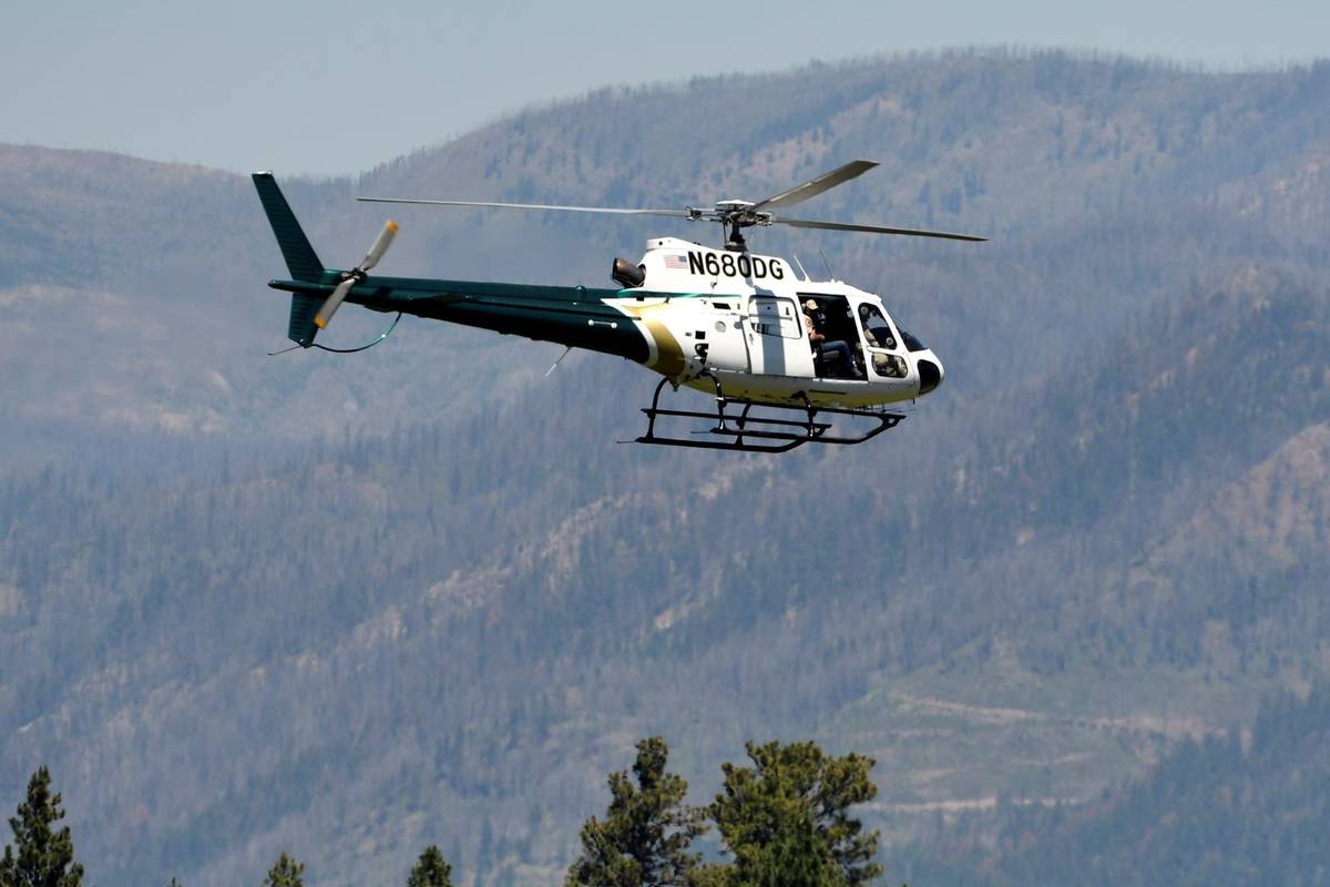 A helicopter from Montana Fish, Wildlife and Parks flies around the Ovando, Mont., area on Tues ...