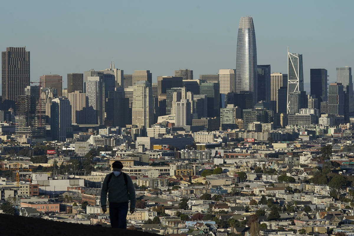 FILE - In this Dec. 7, 2020, file photo, a person wearing a protective mask walks in front of t ...
