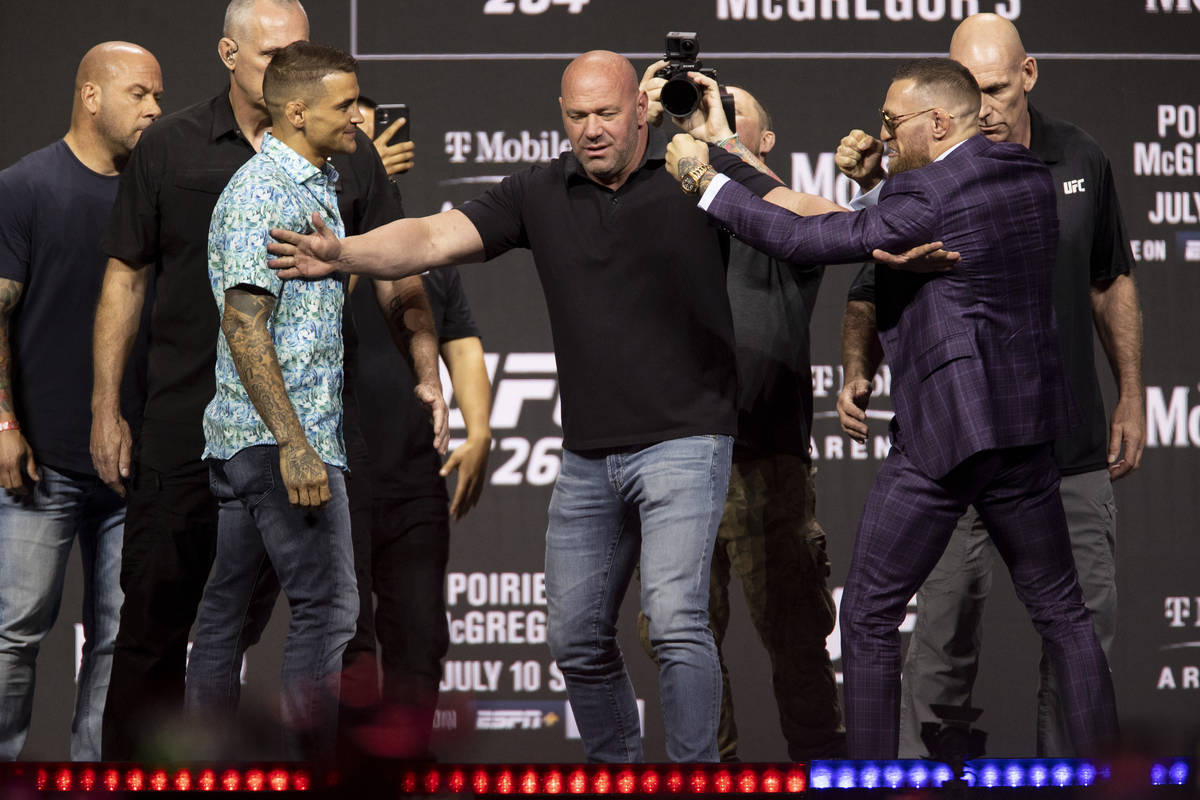 Dana White, center, stands between Dustin Poirier, left, and Conor McGregor during their face o ...