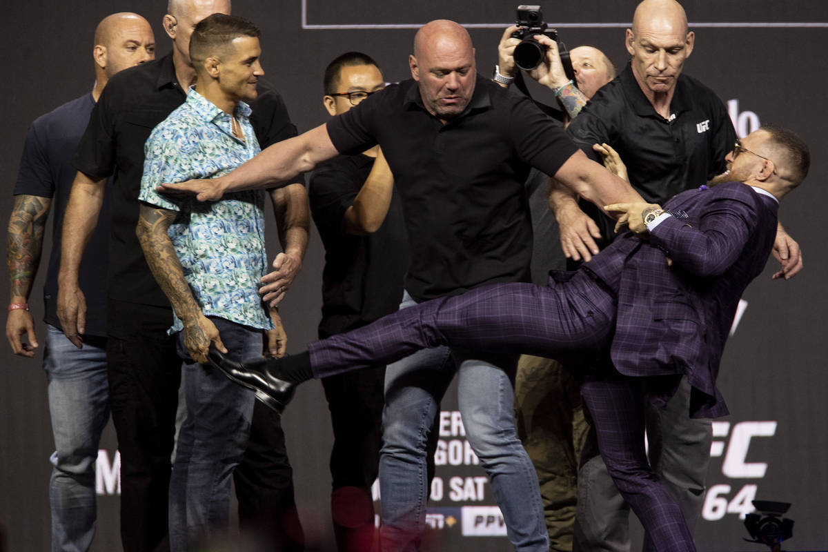 Dana White, center, stands between Dustin Poirier, left, and Conor McGregor during their face o ...