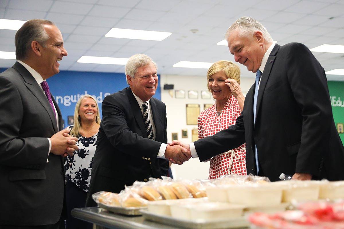 Agriculture Secretary Tom Vilsack, left, shakes hands with Gov. Steve Sisolak, right, next to C ...