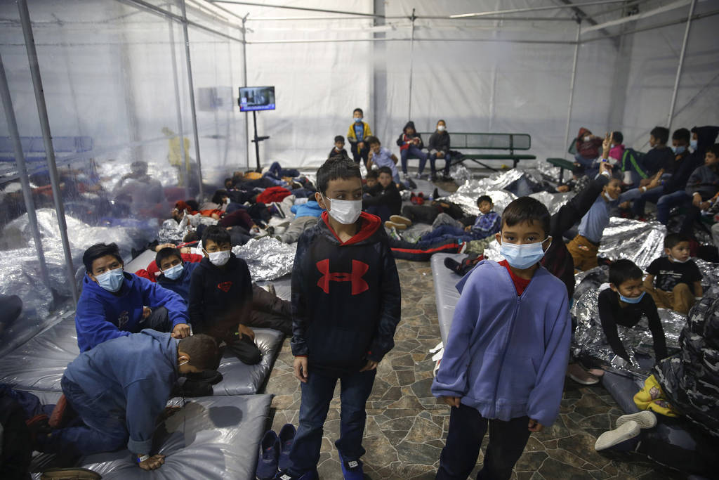 Young children stand or sleep insides a pod at the U.S. Customs and Border Protection holding f ...
