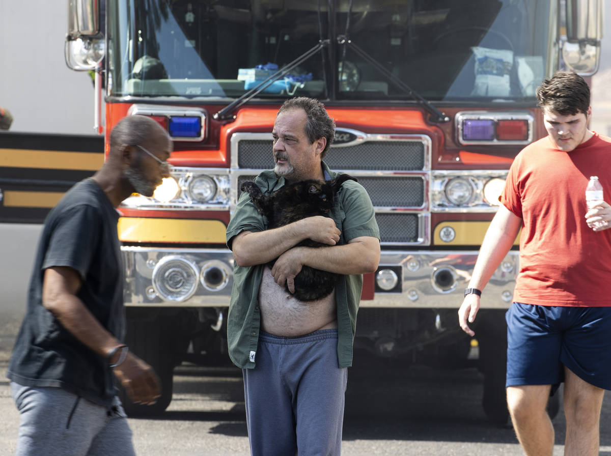 A resident, center, at Bonanza Park Studios holds his cat while being evacuated as Las Vegas fi ...