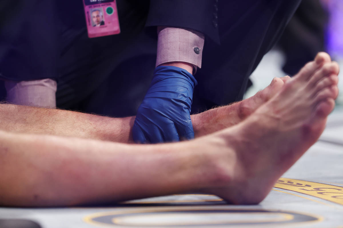 Conor McGregor receives assistance after hurting his foot in the first round of a lightweight b ...