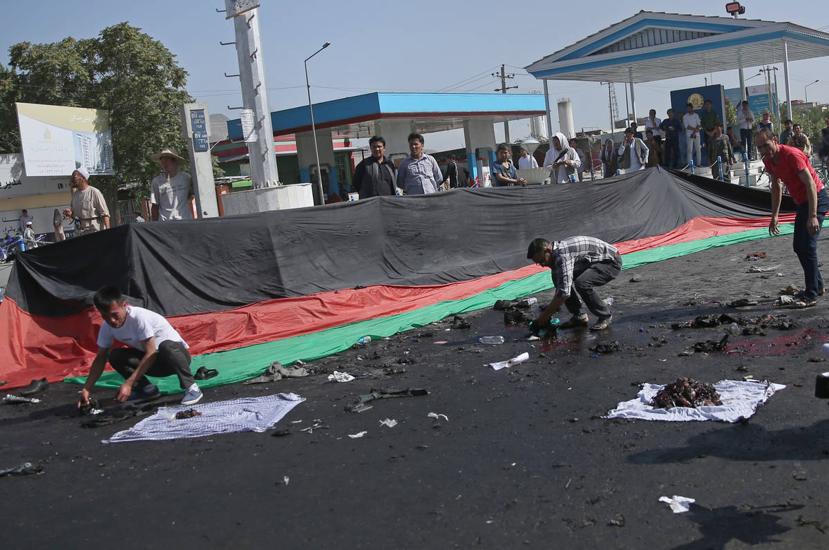 Afghans gather property, left behind by victims of a deadly explosion that struck a protest mar ...