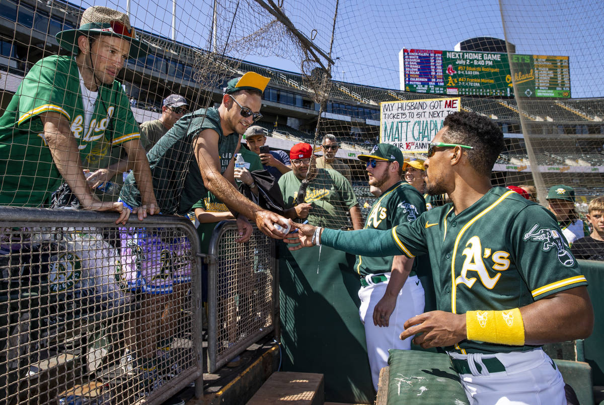 Oakland A‘s infielder Tony Kemp (5, left) and pitcher J.B. Wendelken (57) sign autographs for ...