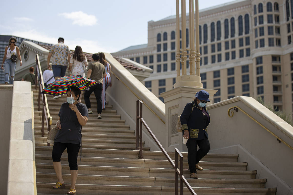 People walk down the stairs of a pedestrian bridge across from the Caesars Palace hotel-casino ...